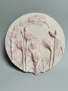 a white plate with pink flowers on the front and back side, against a gray background