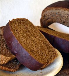 two slices of bread sit on a plate next to another piece of bread that has been cut in half