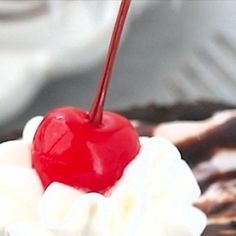 a close up of a dessert with whipped cream and a cherries on top,