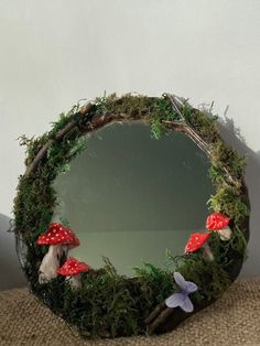 a mirror that is sitting on top of a table with moss and mushrooms around it