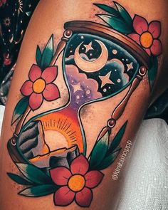 an artistic tattoo design on the leg of a woman's thigh, with flowers around it