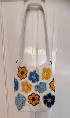 Cute crochet tote bag made with the African flower design. Colourful flowers joined with white. Handle adorned with 2 blue buttons Made in acrylic yarn Made in a smoke free environment  Ready to dispatch White Square Crochet Bag For Vacation, White Square Crochet Bag For Beach, White Square Crochet Beach Bag, White Flower-shaped Shoulder Bag For Everyday Use, White Flower Shoulder Bag For Everyday Use, White Flower-shaped Shoulder Bag For Beach, Casual White Flower-shaped Shoulder Bag, White Crochet Bags For Daily Use, White Crochet Shoulder Bag For Vacation