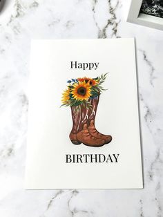 a happy birthday card with boots and sunflowers on the inside, sitting on a marble surface