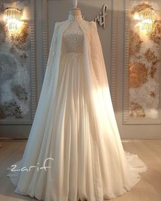 a white wedding dress on display in front of a wall with chandelier lights