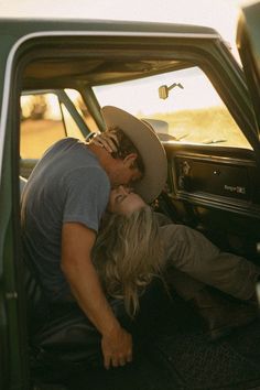 a man and woman kissing in the back of a pick up truck with their head inside