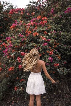 a woman standing in front of flowers with her back to the camera