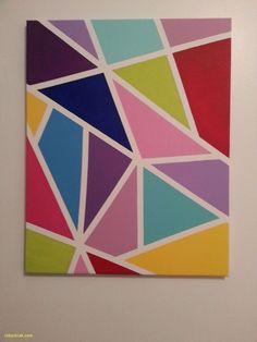 an abstract painting with multicolored shapes on the wall in a white walled room