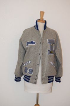 "Back to school, Homecoming or channeling your favorite Princess Di look, this varsity letterman jacket has it all. Heather gray wool varsity letterman jacket with chenille name, date, and varsity Tennis letter makes this a fun take on fall warmth.  Royal blue accent stripes at waistband, cuffs and standup collar as well as patch accents.  Coat belonged to Julia from Ingrahm High School in Seattle WA, and is ready for you to wear as is or switch out to your own name, date and school.  Custom made by TM Athletics.  Lined, metal snaps. Free of rips, stains and odor.     Women's oversize small to medium Measurements: Back of neck to bottom of jacket:  26\" Shoulder to shoulder at back:  18\" Top of sleeve to bottom of cuff:  23\" Under arm seam:  15\" Armpit to armpit:  25\"   Side to side at School Varsity Jacket With Ribbed Cuffs, Collegiate Varsity Jacket With Baseball Collar For School, Collegiate Outerwear With Ribbed Cuffs For School, College Style Varsity Jacket For Winter School, Winter College Style Varsity Jacket For School, Sporty Varsity Jacket For School Winter Season, Sporty Varsity Jacket For School In Winter, Sporty Winter Varsity Jacket For School, Collegiate Winter Outerwear For School