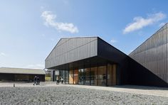 two people are walking in front of a building that has black siding on the side