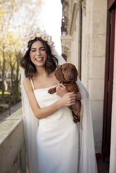 a woman in a wedding dress holding a dog