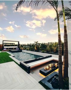 an outdoor living area with palm trees and fire pit in the center, surrounded by grass