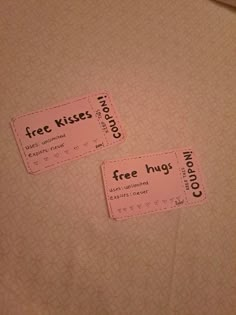 two coupons sitting on top of a bed next to each other with the words free kisses