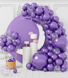 purple balloons are arranged around a cake and other items in front of a white wall