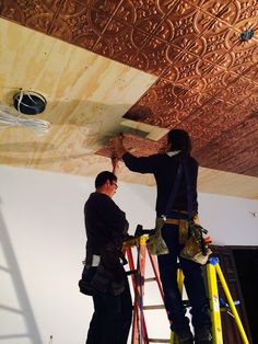 two men working on a ceiling in a room