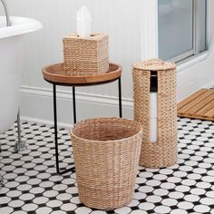 two wicker baskets sitting on top of a black and white floor next to a bath tub