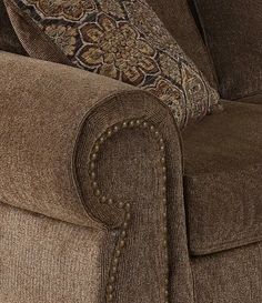 the back end of a brown couch with decorative pillows on it and a pillow that has been