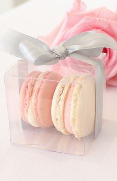 three macaroons are in a clear box with a bow on the top one