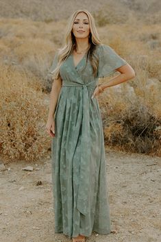 a woman standing in the desert wearing a green dress