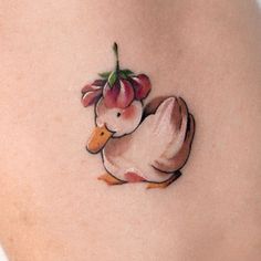 a small tattoo of a duck with flowers on it's back side ribcage