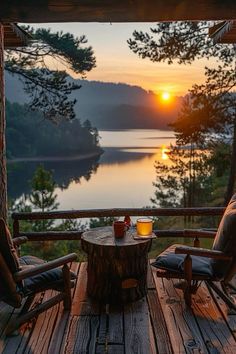 two chairs sitting on top of a wooden deck next to a table with drinks in front of a lake