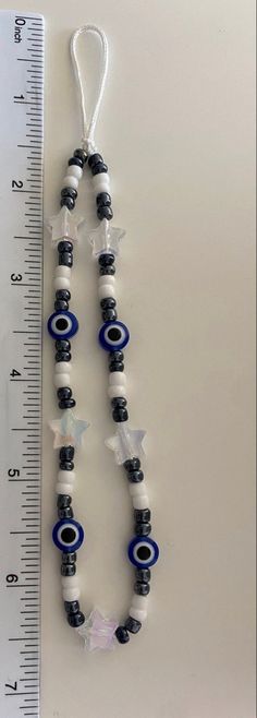 an evil eye beaded necklace is displayed next to a ruler on a white surface