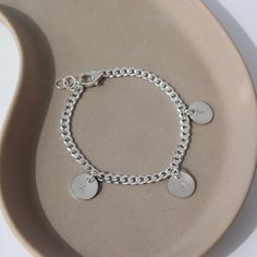 925 sterling silver Carter Personalized disc Bracelet laid on a gray plate in the sunlight. This bracelet features the Carter chain then followed Initial stamped disc. Sterling Silver Charm Bracelet With Initials In Silver, Sterling Silver Hand-stamped Bracelet, Silver Charm Bracelet With Initials As Gift, Silver Charm Bracelet With Initials For Gift, Minimalist Sterling Silver Name Bracelet For Friendship, Minimalist Sterling Silver Friendship Name Bracelet, Minimalist Charms Bracelet For Personalized Gift, Adjustable Hand Stamped Sterling Silver Bracelet, Everyday Bracelets With Charms