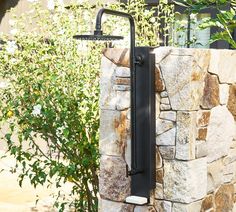 a faucet mounted to the side of a stone wall next to a tree