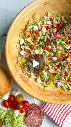 a wooden bowl filled with salad next to bread