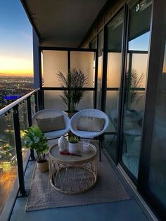 two chairs and a table on a balcony overlooking the city at sunset or dawn,