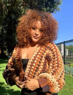 a woman standing in the grass wearing a crocheted shawl over her shoulders