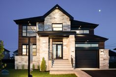 a modern home at night with lights on the front door and steps leading up to it