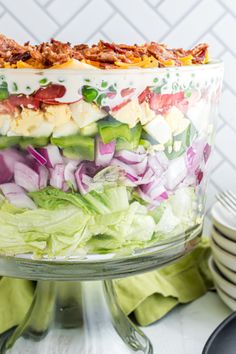 a layered salad with lettuce, tomatoes, onions and other toppings in a glass dish