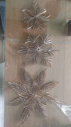 three metal snowflakes on display in a glass case next to a wall