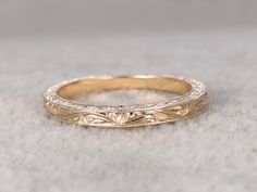 a gold wedding band that has been engraved with leaves and scrolls on the inside of it