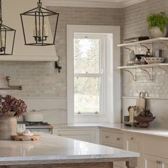 a kitchen filled with lots of counter top space and hanging lights over the stovetop