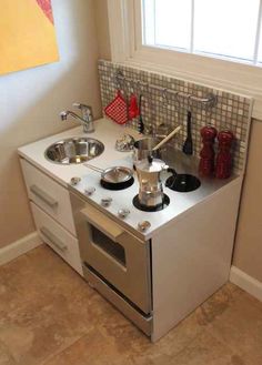 a small stove top oven sitting in a kitchen next to a sink and counter with pots and pans on it