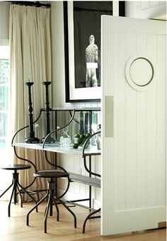 an open door leading to a dining room with white walls and wood flooring on the side