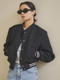 This is a varsity jacket with a classic yet minimalist vibe. Wool blend fabric with a soft touch and subtle luster was used, and a separate interlining was reinforced to make the silhouette more sturdy. Color-coordinated ribs are used at the ends to add a more casual mood, and tone-on-tone colored logos are embroidered on the sides of the pockets.- Oversized fit makes it comfortable to wear- Opens and closes with snap buttons that do not damage the design- You can feel chic by emphasizing the shoulder line.- Inter-seasonal thickness allows for use in a variety of looks*The color of the product is closer to the actual color in the detailed cut than in the cut worn by the model due to lighting. There may be slight differences in color depending on the type of monitor and environment. Classic Navy Varsity Jacket For College, Classic Varsity Jacket For Streetwear, Navy Varsity Jacket With Pockets For Fall, Classic Fall Outerwear For College, Classic Baseball Collar Outerwear For Work, Navy Varsity Jacket For Work And Fall, Classic Outerwear With Baseball Collar For Winter, Classic Outerwear With Baseball Collar For Work, Classic Navy Varsity Jacket For Fall