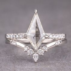 a white gold engagement ring with a pear shaped cut diamond in the center and side stones