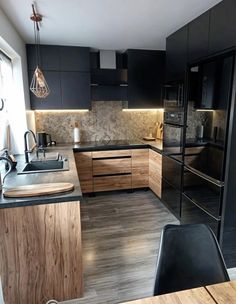 a kitchen with black cabinets and wood flooring