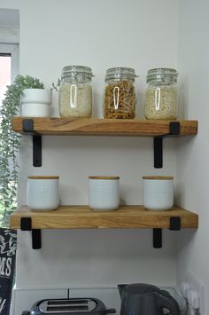 three wooden shelves with jars on them above an electric stove top burner and toaster