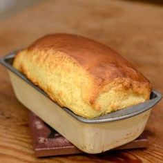 a loaf of bread sitting in a tin on top of a wooden table