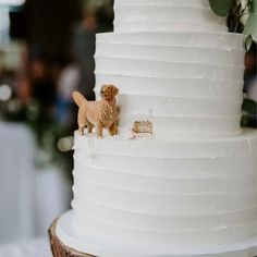 a small dog figurine sitting on top of a white tiered wedding cake