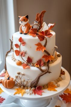 a three tiered cake decorated with fall leaves and an animal figurine on top