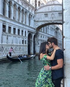 a man and woman are kissing in front of a gondola on the water