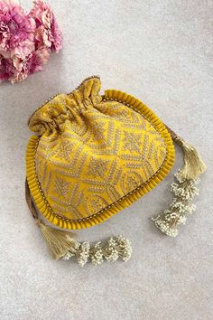 "Our Leela heritage potli is pure class and opulence. The beauty lies in heavy detailed handcrafted tassles that add the weight to this potli and will charm everyone off their feet! Colour: Yellow with goldembroidery Embroidered front and back. Dimensions (LxB): 8.5\"x 9.5\" (22 cm x 24 cm) Handle drop: 5\" (13 cm) Material : Embroidered poly silk, gold tissue, poly satin lining, woven gold thread drawstrings and woven thread handle, handcrafted tassels." Studio Iris, Embroidered Clutch, Potli Bags, Gold Embroidery, Gold Thread, Jute Bags, Silk Embroidery, Gold Threads, Anniversary Gift For Her