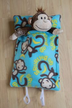 a stuffed monkey laying on top of a blue and yellow pillow with monkeys on it