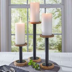 three candles are sitting on a table with silverware