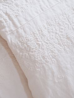 an unmade bed with white sheets and pillows