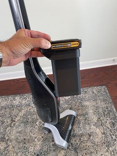 a hand is holding the handle on a vacuum that's attached to a rug